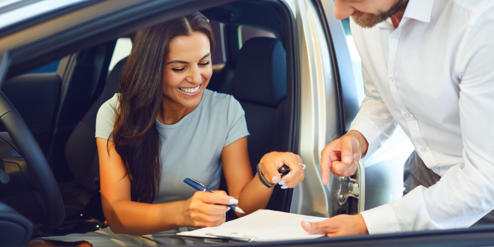 a lady buying a car and signing the car finance paperwork